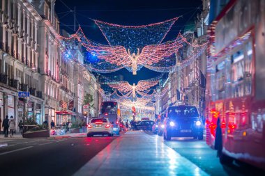 Londra İngiltere - 18 Kasım 2021: Regent caddesinde şenlik dekorasyonları ve Noel ışıkları, arabalar, otobüsler ve sokakta yürüyen insanlar. Londra 'nın gece hayatı 