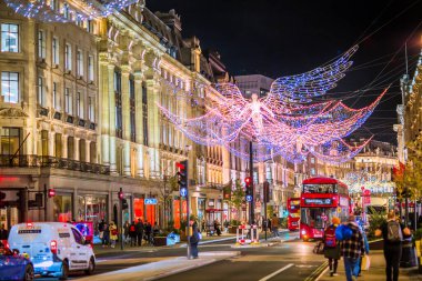Londra İngiltere - 18 Kasım 2021: Regent caddesinde şenlik dekorasyonları ve Noel ışıkları, arabalar, otobüsler ve sokakta yürüyen insanlar. Londra 'nın gece hayatı 