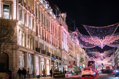 Londra İngiltere - 18 Kasım 2021: Regent caddesinde şenlik dekorasyonları ve Noel ışıkları, arabalar, otobüsler ve sokakta yürüyen insanlar. Londra 'nın gece hayatı 
