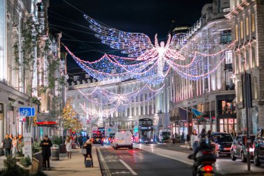 Londra İngiltere - 18 Kasım 2021: Regent caddesinde şenlik dekorasyonları ve Noel ışıkları, arabalar, otobüsler ve sokakta yürüyen insanlar. Londra 'nın gece hayatı 