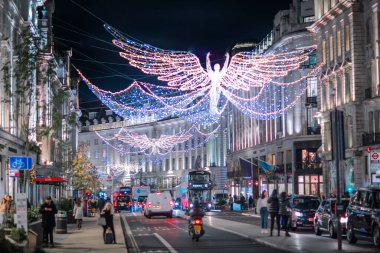 Londra İngiltere - 18 Kasım 2021: Regent caddesinde şenlik dekorasyonları ve Noel ışıkları, arabalar, otobüsler ve sokakta yürüyen insanlar. Londra 'nın gece hayatı 