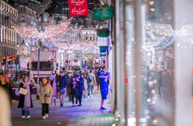 Londra İngiltere - 18 Kasım 2021: Regent caddesinde şenlik dekorasyonları ve Noel ışıkları, arabalar, otobüsler ve sokakta yürüyen insanlar. Londra 'nın gece hayatı 