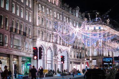 Londra İngiltere - 18 Kasım 2021: Regent caddesinde şenlik dekorasyonları ve Noel ışıkları, arabalar, otobüsler ve sokakta yürüyen insanlar. Londra 'nın gece hayatı 