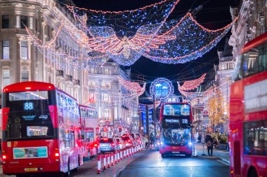 Londra İngiltere - 18 Kasım 2021: Regent caddesinde şenlik dekorasyonları ve Noel ışıkları, arabalar, otobüsler ve sokakta yürüyen insanlar. Londra 'nın gece hayatı 