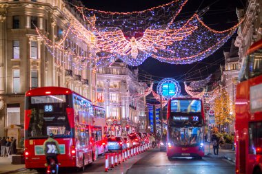 Londra İngiltere - 18 Kasım 2021: Regent caddesinde şenlik dekorasyonları ve Noel ışıkları, arabalar, otobüsler ve sokakta yürüyen insanlar. Londra 'nın gece hayatı 