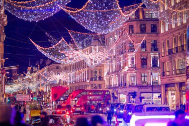 Londra İngiltere - 18 Kasım 2021: Regent caddesinde şenlik dekorasyonları ve Noel ışıkları, arabalar, otobüsler ve sokakta yürüyen insanlar. Londra 'nın gece hayatı 