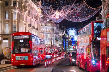 Londra İngiltere - 18 Kasım 2021: Regent caddesinde şenlik dekorasyonları ve Noel ışıkları, arabalar, otobüsler ve sokakta yürüyen insanlar. Londra 'nın gece hayatı 