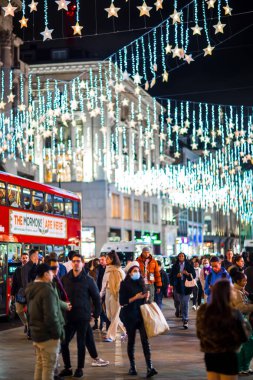 Londra İngiltere - 18 Kasım 2021: Oxford caddesinde festival dekorasyonları ve Noel ışıkları, arabalar, otobüsler ve sokakta yürüyen insanlar. Londra 'nın gece hayatı 