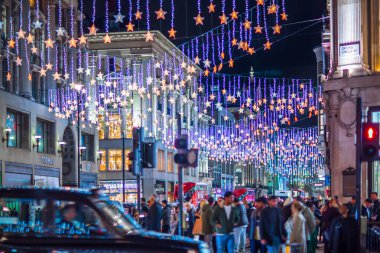 Londra İngiltere - 18 Kasım 2021: Oxford caddesinde festival dekorasyonları ve Noel ışıkları, arabalar, otobüsler ve sokakta yürüyen insanlar. Londra 'nın gece hayatı 