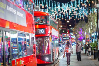 Londra İngiltere - 18 Kasım 2021: Oxford caddesinde festival dekorasyonları ve Noel ışıkları, arabalar, otobüsler ve sokakta yürüyen insanlar. Londra 'nın gece hayatı 