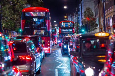 Londra İngiltere - 18 Kasım 2021: Oxford caddesinde festival dekorasyonları ve Noel ışıkları, arabalar, otobüsler ve sokakta yürüyen insanlar. Londra 'nın gece hayatı 
