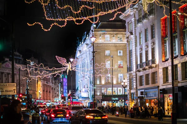 Londra İngiltere - 18 Kasım 2021: Piccadilly Caddesi 'nde festival dekorasyonları ve Noel ışıkları. Bir sürü araba ve karşıdan karşıya geçen insanlar.