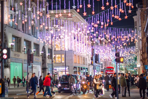 Londra İngiltere - 18 Kasım 2021: Oxford caddesinde festival dekorasyonları ve Noel ışıkları, arabalar, otobüsler ve sokakta yürüyen insanlar. Londra 'nın gece hayatı 