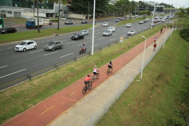 Salvador, Bahia, Brezilya - 30 Eylül 2021: Salvador 'da bir araç yolunun yanında bisiklet yolu üzerinde seyahat eden bisikletçi.