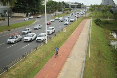 Salvador, Bahia, Brezilya - 30 Eylül 2021: Salvador 'da bir araç yolunun yanında bisiklet yolu üzerinde seyahat eden bisikletçi.