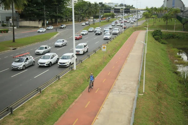 Salvador, Bahia, Brezilya - 30 Eylül 2021: Salvador 'da bir araç yolunun yanında bisiklet yolu üzerinde seyahat eden bisikletçi.
