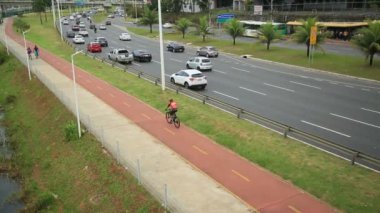 Salvador, Bahia, Brezilya - 30 Eylül 2021: Salvador 'da bir araç yolunun yanında bisiklet yolu üzerinde seyahat eden bisikletçi.