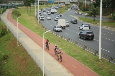 Salvador, Bahia, Brezilya - 30 Eylül 2021: Salvador 'da bir araç yolunun yanında bisiklet yolu üzerinde seyahat eden bisikletçi.