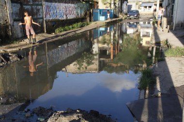 Salvador, Bahia, Brezilya - 2 Mayıs 2013: Salvador şehrindeki bir caddede biriken kanalizasyon suyunun yakınında genç bir adam görüldü.