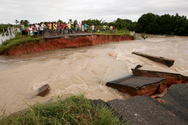 Prado, Bahia, Brezilya - 7 Nisan 2010: Prado şehrindeki bir nehrin taşması sonucu yıkılmış bir yolu geçmeye çalışan insanlar