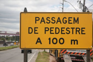 Salvador, Bahia, Brezilya - 11 Nisan 2022: BR 324 karayolundaki trafik levhası 100 metre ötede yaya geçidi olduğunu gösteriyor..