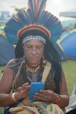 Salvador, Bahia, Brezilya - 25 Nisan 2022: Pataxo etnik kökenli yerli halk Salvador şehrindeki bir kampta internete erişmek için cep telefonu kullanıyor..