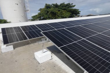 Salvador, Bahia, Brezilya - Haziran 6, 2022: Salvador şehrindeki bir devlet okulunun çatısında güneş enerjisi üretim panelleri ile çalışan işçi.