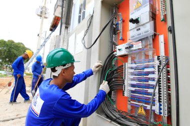 itabuna, bahia, brazil - may 23, 2022: electrician working on electrical distribution board of a school under construction in the city of Itabuna. clipart