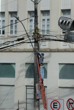 Salvador, Bahia, Brezilya - 20 Haziran 2022: Merdivendeki adam Salvador şehrindeki elektrik direğine kablo döşedi.