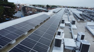 Salvador, Bahia, Brezilya - Haziran 6, 2022: Salvador şehrindeki bir devlet okulunun çatısında güneş enerjisi üretim panelleri ile çalışan işçi.