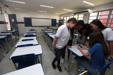 Santana, Bahia, Brezilya - 13 Eylül 2022: Santana şehrinde tam zamanlı bir devlet okulunun sınıfında akıllı telefon kullanan öğrenciler.