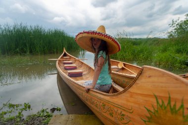 The young lady in the sombrero is in a canoe.