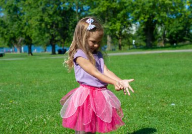 Pembeli küçük kız çimlerin üzerinde bir şey gösteriyor..