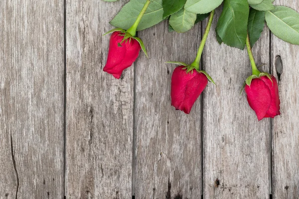 Três rosas vermelhas no fundo de madeira — Fotografia de Stock