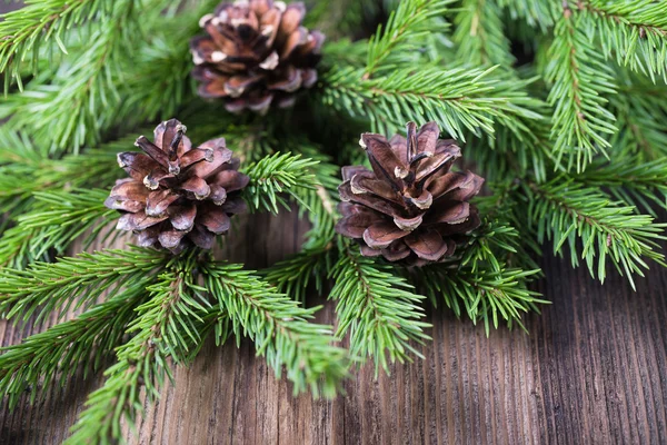 Fir tree twigs with three cones on old wooden table — Stock Photo, Image