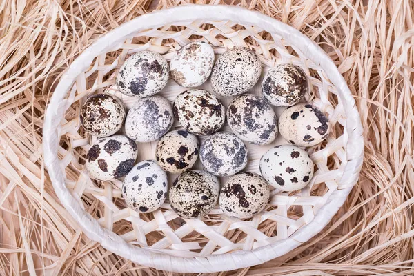 Ovos de codorna em uma cesta de vime com palha, vista superior — Fotografia de Stock