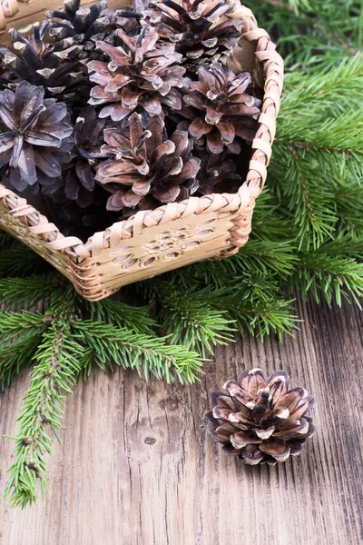 Basket with pine cones on wooden background — Stock Photo, Image