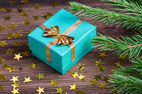 Christmas gift with stars and fir tree branch on wooden table — Stock Photo, Image