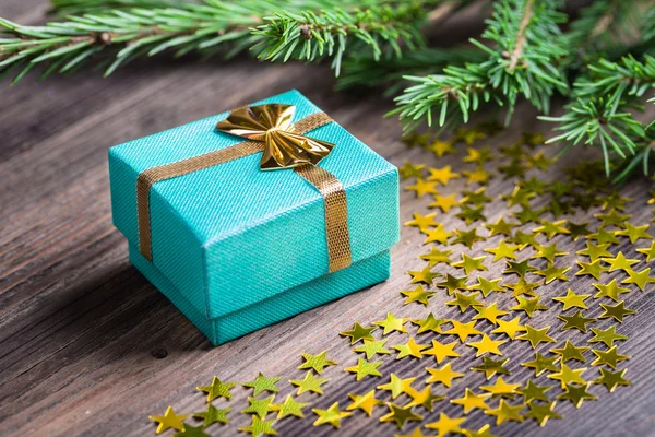 De gift van Kerstmis met sterretjes en zwarte spar boom takje op houten tafel — Stockfoto