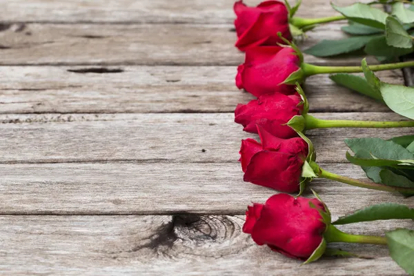 Cinco rosas vermelhas em fundo de madeira, foco seletivo — Fotografia de Stock