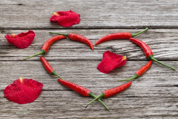 Červené chilli papričky ve tvaru srdce s růží — Stock fotografie