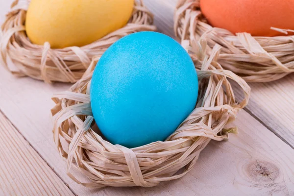 Uova di Pasqua in piccoli nidi su sfondo di legno — Foto Stock