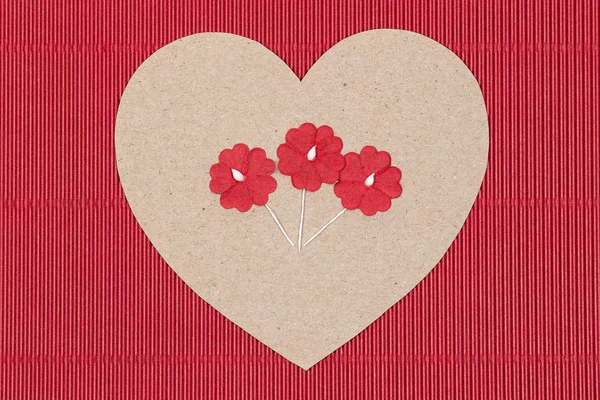 Coeur en carton avec fleurs en papier sur fond rouge . — Photo