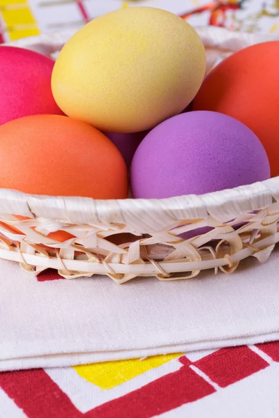 Huevos de colores en una canasta sobre la mesa —  Fotos de Stock