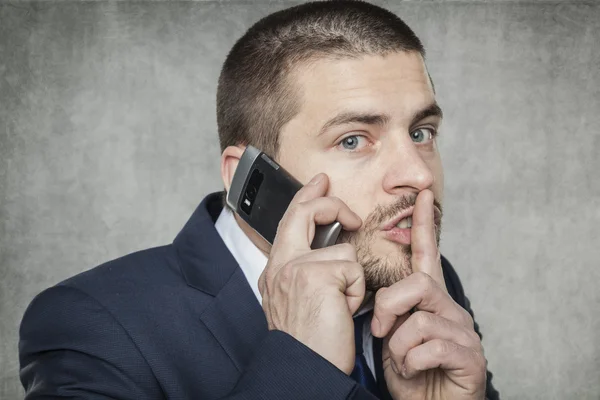 Бизнесмен разговаривает по телефону и просит тишины — стоковое фото