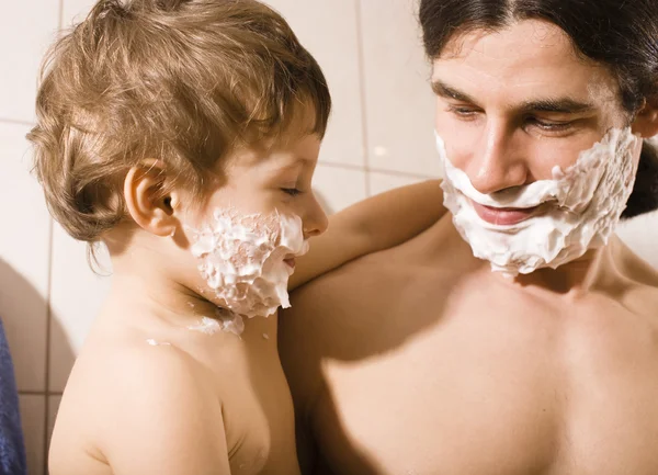 Portrait of son and father enjoying while shaving together