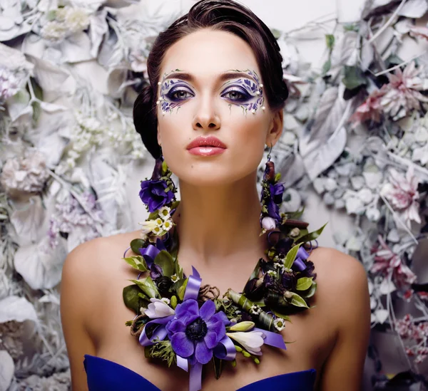 Floral face art with anemone in jewelry, sensual young brunette woman