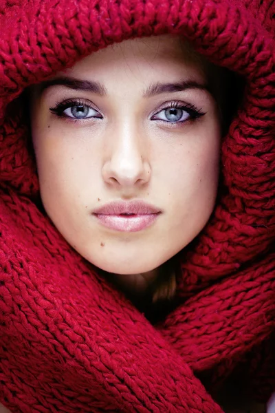 Young pretty woman in sweater and scarf all over her face
