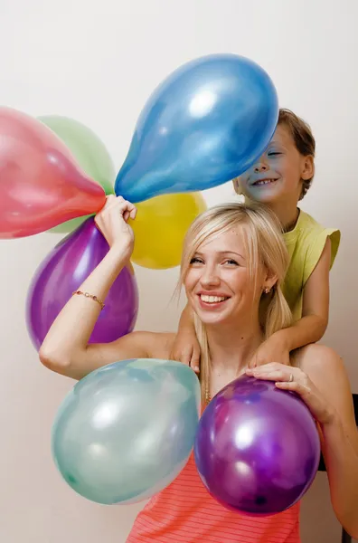Pretty family with color balloons on white background, blond woman with little boy