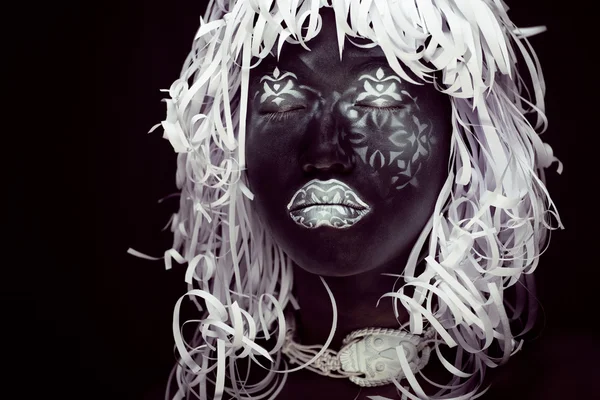 Creative make up like Ethiopian mask, white pattern on black face close up